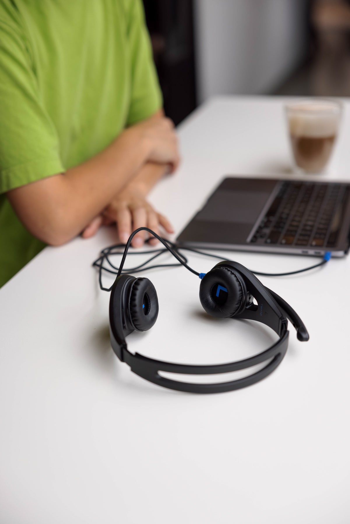 TWT Audio ERGO headset on a table at a coffeeshop plugged in to a laptop