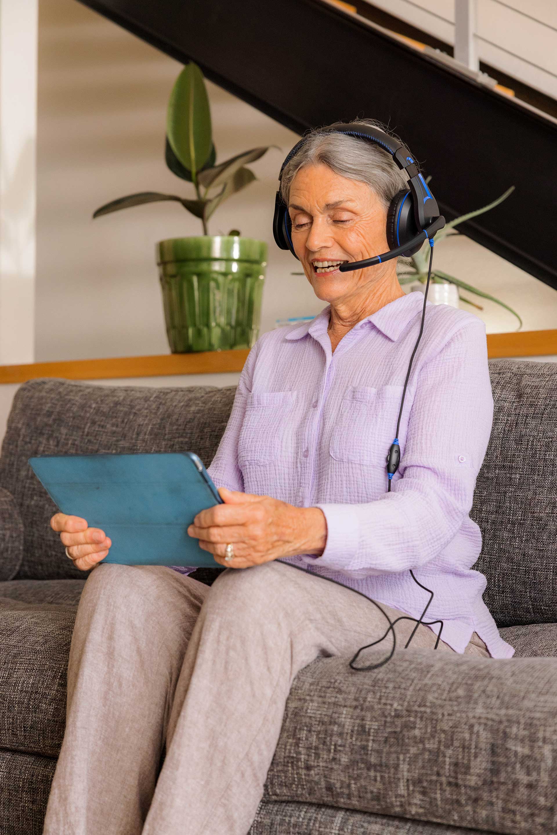 A woman waring TWT Audio DURO headphones to talking with her family on a video call through a tablet