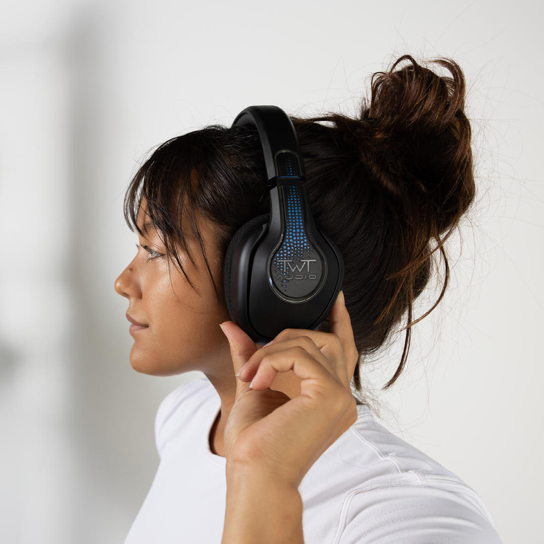 A woman in a white shirt glancing to the right enjoying her seamless listening experience with TWT Audio's TW340 headphones.