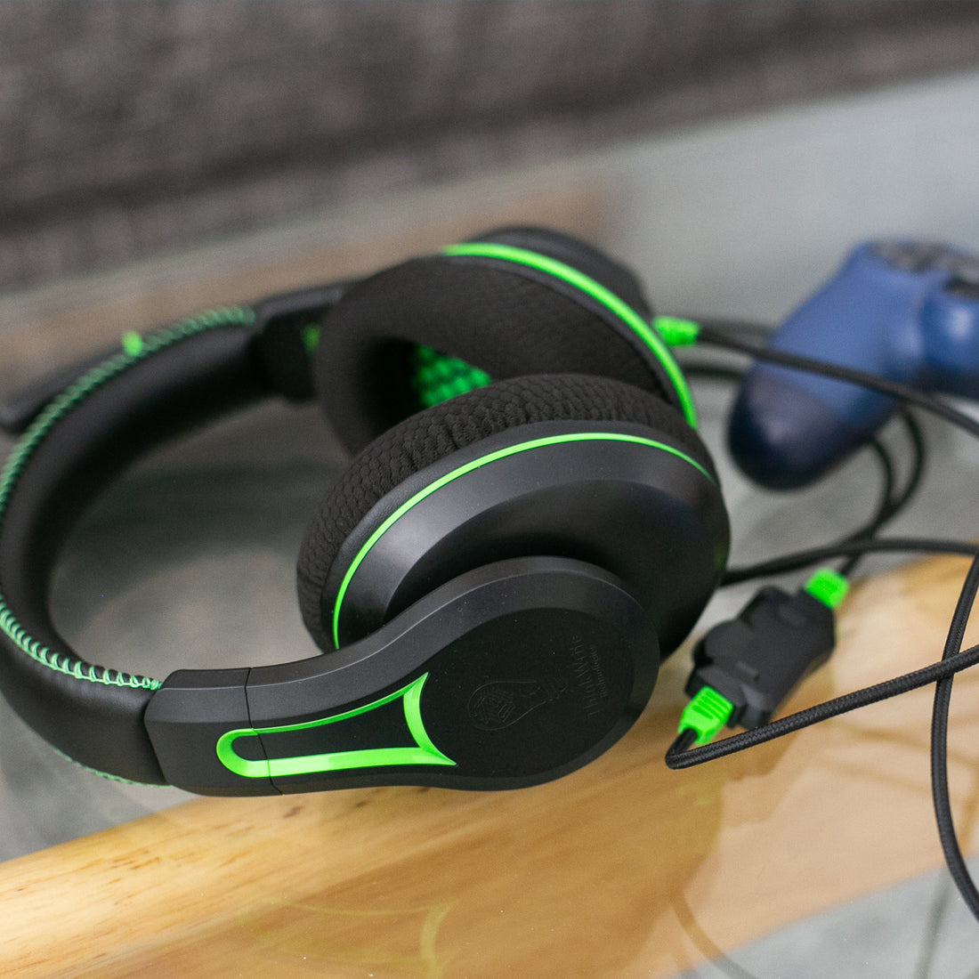 The 250XG Victory Gaming Headset by TWT Audio lying on a desk, next to a video game controller.